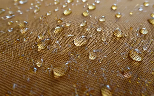 Gouttes d'eau perlant sur un tissu imperméabilisé